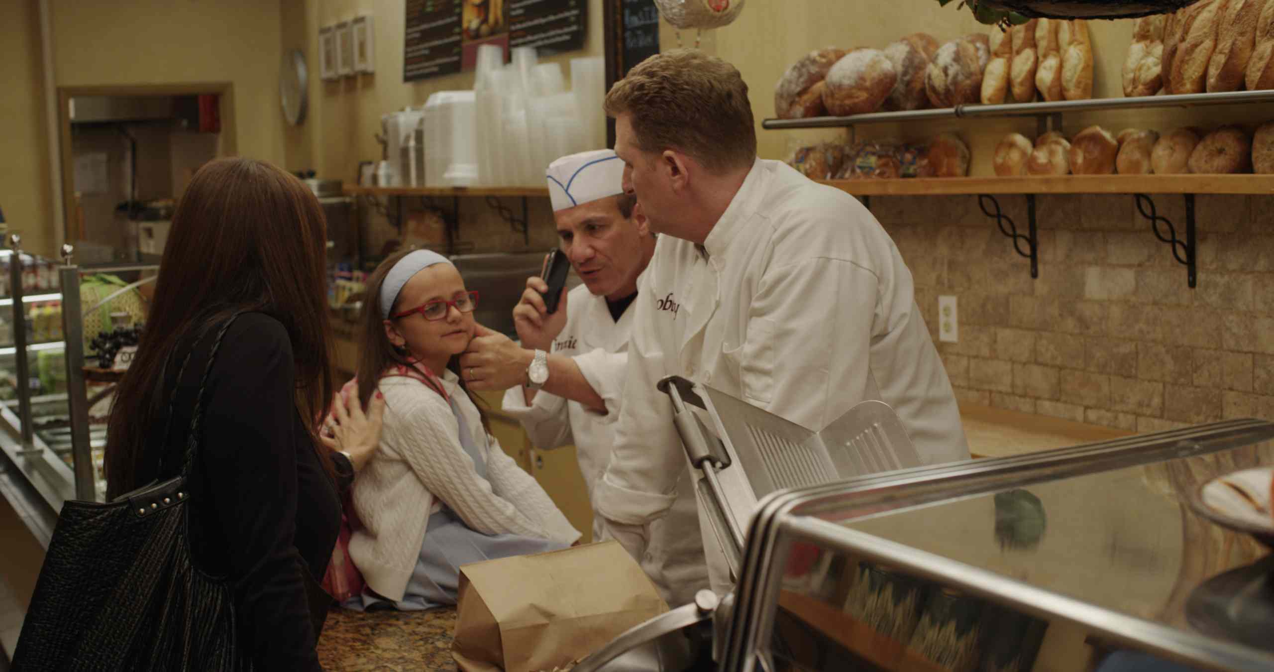 Olivia  during a scene at a Middle Village deli with actor Michael Rapaport (far right).