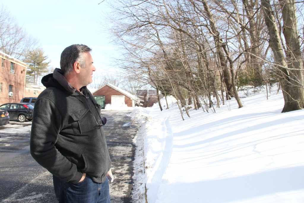 John Hatzopoulos stands at the border between the co-ops and a long strip of endangered wooded land.