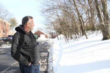 John Hatzopoulos stands at the border between the co-ops and a long strip of woodland that is on the precipice between being saved or destroyed.