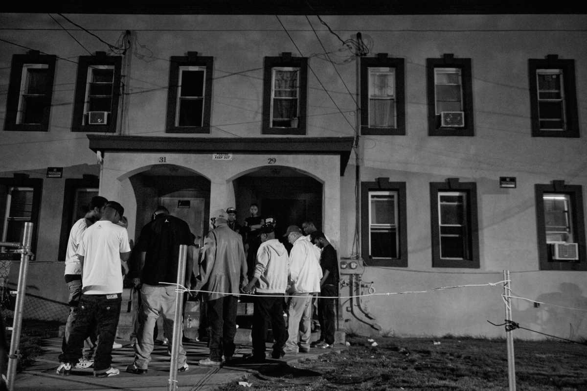 A photo from the book shows members of the All Saints Temple and community activists hold hands with members of the community living in the Linden Triangle of Hempstead during a midnight prayer march (June 16, 2012).