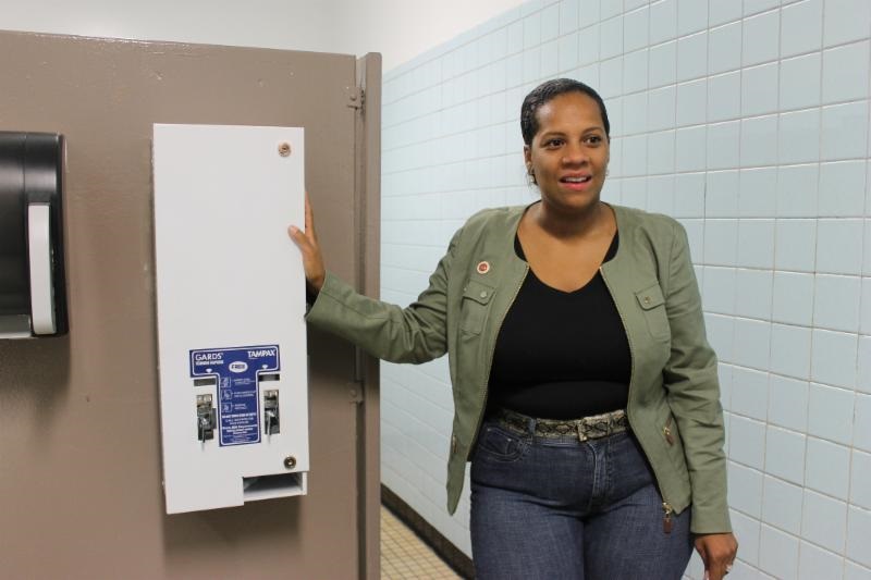 Councilwoman Julissa Ferreras-Copeland is pictured standing next to the free feminine products dispenser installed in the girls' bathroom at the High School for Arts and Business in Corona.