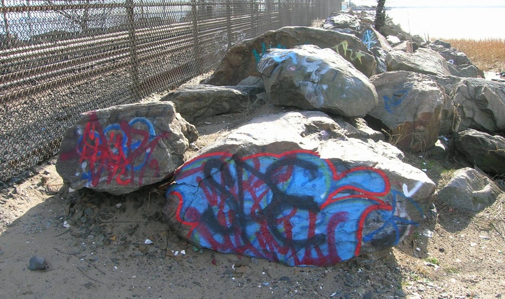 Graffiti-scarred boulders are shown adjacent to the southbound A train tracks in Hamilton Beach.