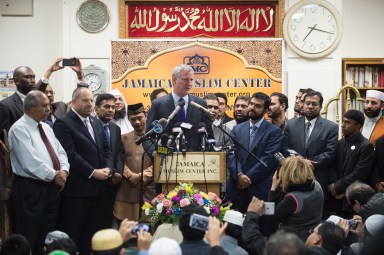 Flanked by city officials and representatives of Queens' Muslim community, Mayor Bill de Blasio speaks to guests at the Jamaica Mosque Center on Friday.