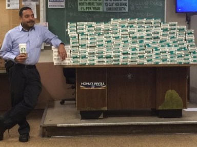 Deputy Inspector Jeffrey Schiff, 106th Precinct commander, shown next to a pile of untaxed cigarette cartons that the precinct seized last week.