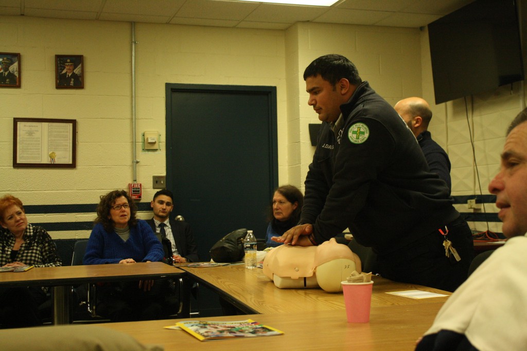 EMT Jeremy Davis demonstrating how to perform CPR at last week's 112th Precinct Community Council meeting.