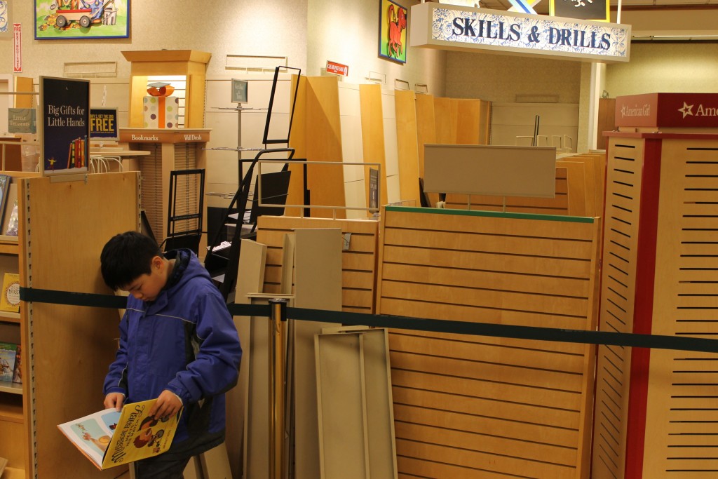 A child reads near a cordoned-off section of empty bookshelves.