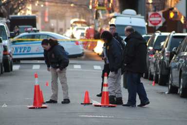 Police examine the scene where a 31-year-old man was shot to death in Woodside on Saturday morning.