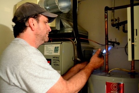Plumber_soldering_pipe_above_new_water_heater