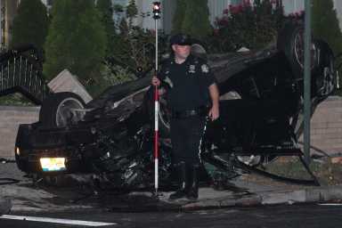 A police officer stands in front of an overturned Audi sedan following a deadly crash in South Ozone Park on Sept. 11.