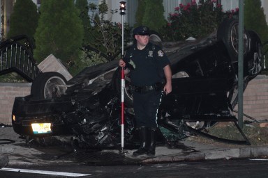 A police officer stands in front of an overturned Audi sedan following a deadly crash in South Ozone Park on Sept. 11.