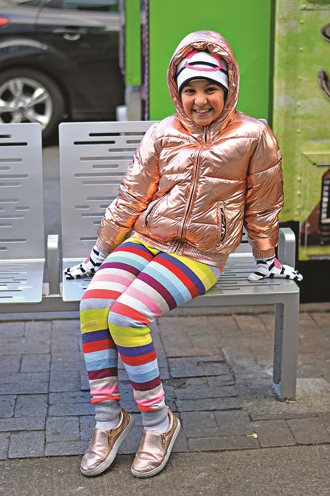 This is mini fashionista Kenzy, who had stopped with her mom to pick up the ultimate accessory — a falafel! Kenzy stood out from the crowd with her rose gold coat and sneakers paired with rainbow leggings. Her favorite subject in school is math.