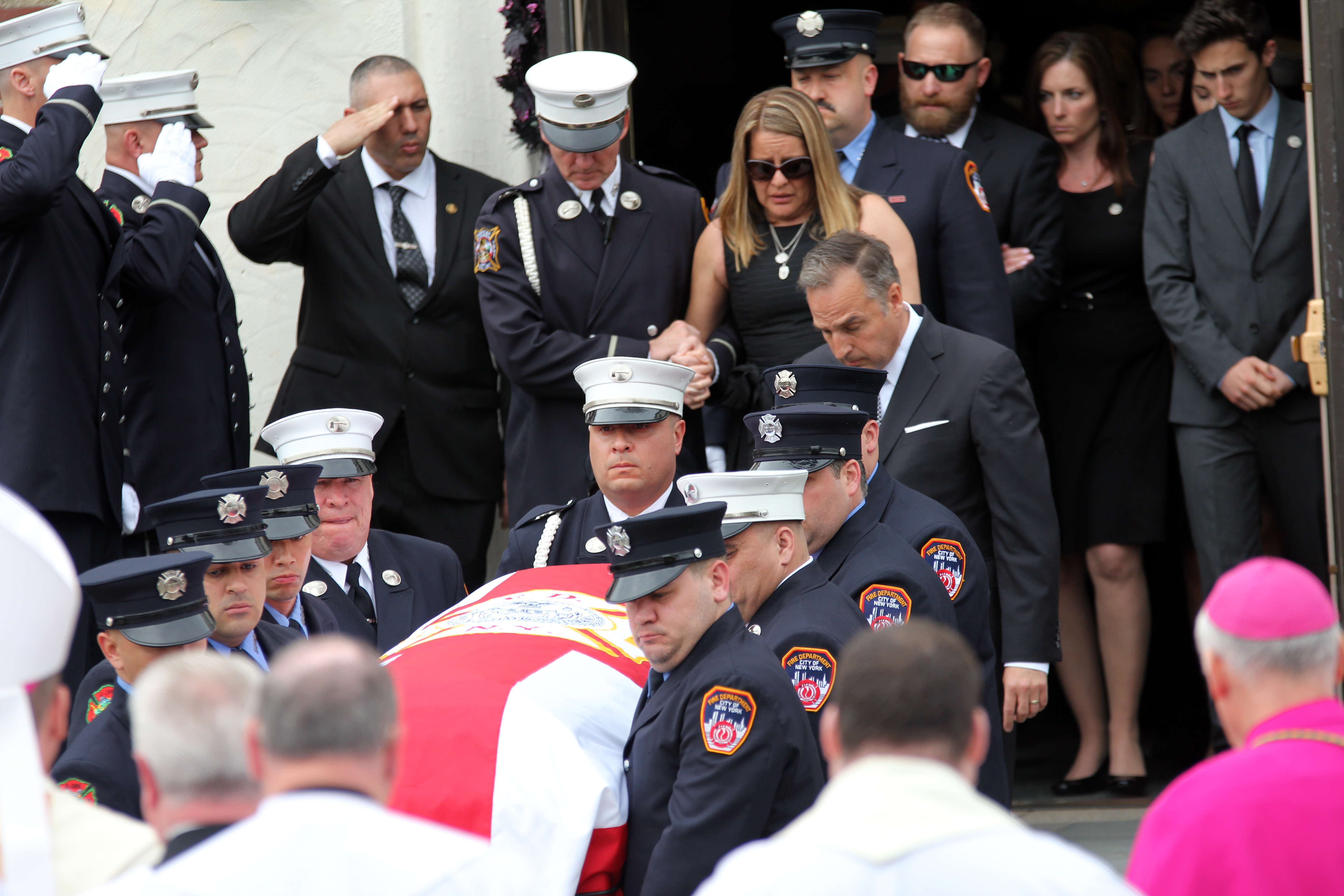 Firefighters carry the body of Firefighter William Tolley out of St. Martin's of Tours Church as his widow, Marie Tolley, follows.