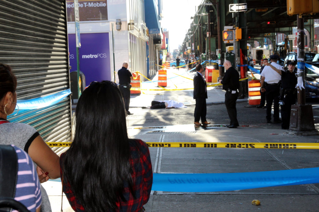 Bystanders watch as police and the Medical Examiner's office investigate the death of a man who fell from the 82nd Street station above Roosevelt Avenue in Jackson Heights on June 20.