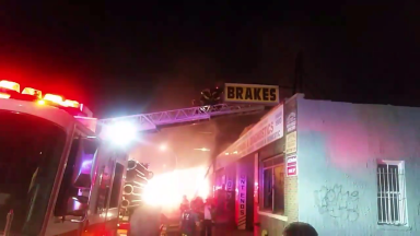 A firefighter scales the ladder during a three-alarm fire at a Middle Village garage on July 2.