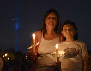Middle Village residents held a memorial vigil on Monday night on the 16th anniversary of the 9/11 terrorist attacks. The Tribute in Light can be seen in the background.