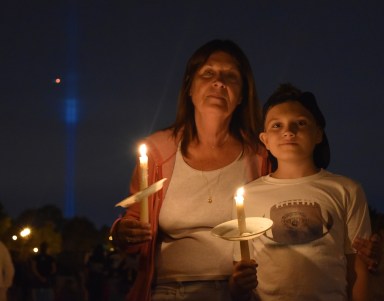 Middle Village residents held a memorial vigil on Monday night on the 16th anniversary of the 9/11 terrorist attacks. The Tribute in Light can be seen in the background.