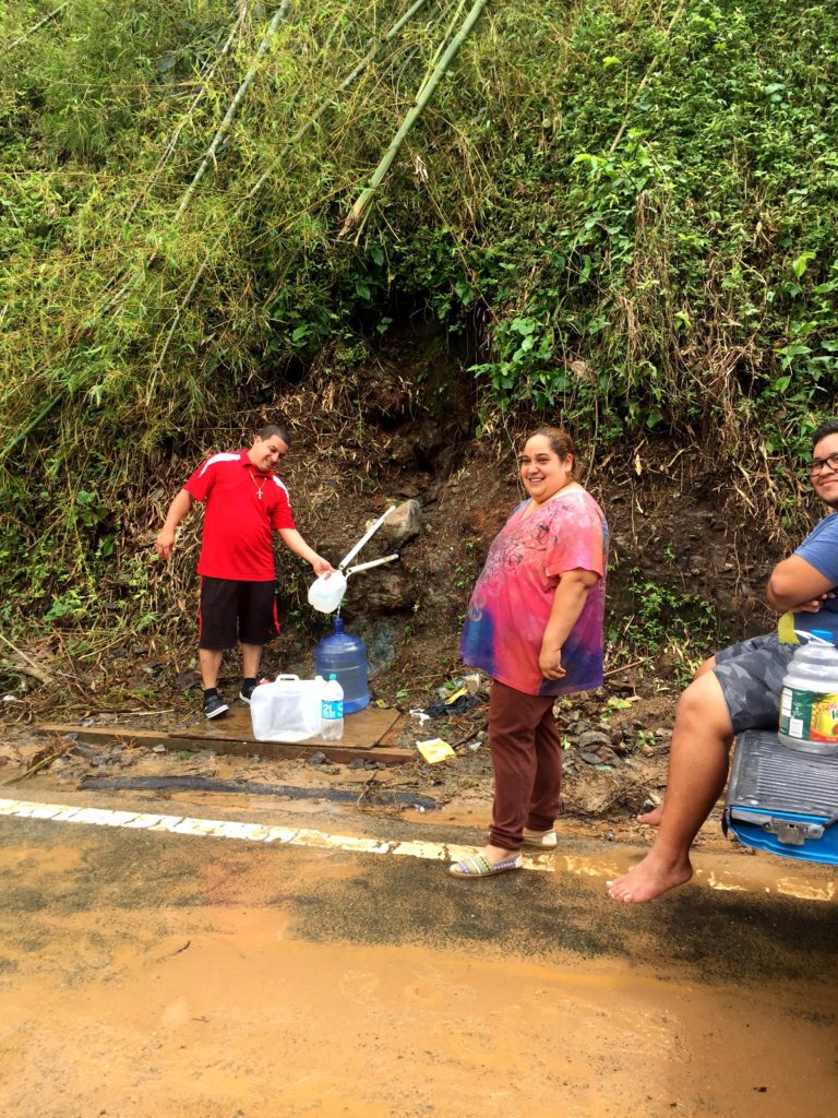 A family gathers water from a pvc pipe. 