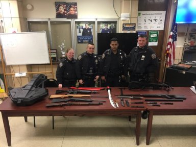 Officers from the 109th Precinct stand before the cache of weapons seized from a Flushing home on Feb. 16.