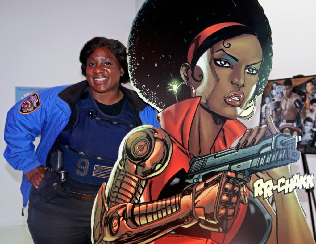Detective Tanya Duhaney of the 113 Precinct Community Affairs poses with a cardboard cut-out of comic book character Misty Knight.