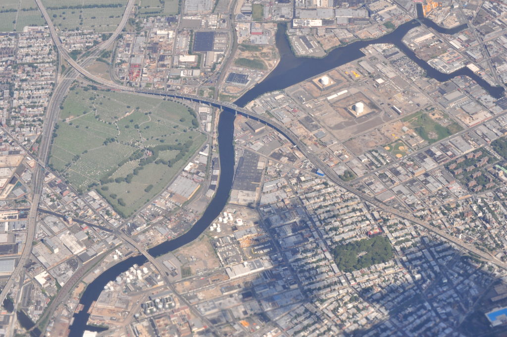 This overhead photo taken in 2013 shows much of the Newtown Creek and the surrounding area. The original Kosciuszko Bridge and Brooklyn-Queens Expressway run through the heart of the picture. (Photo via Wikimedia Commons)