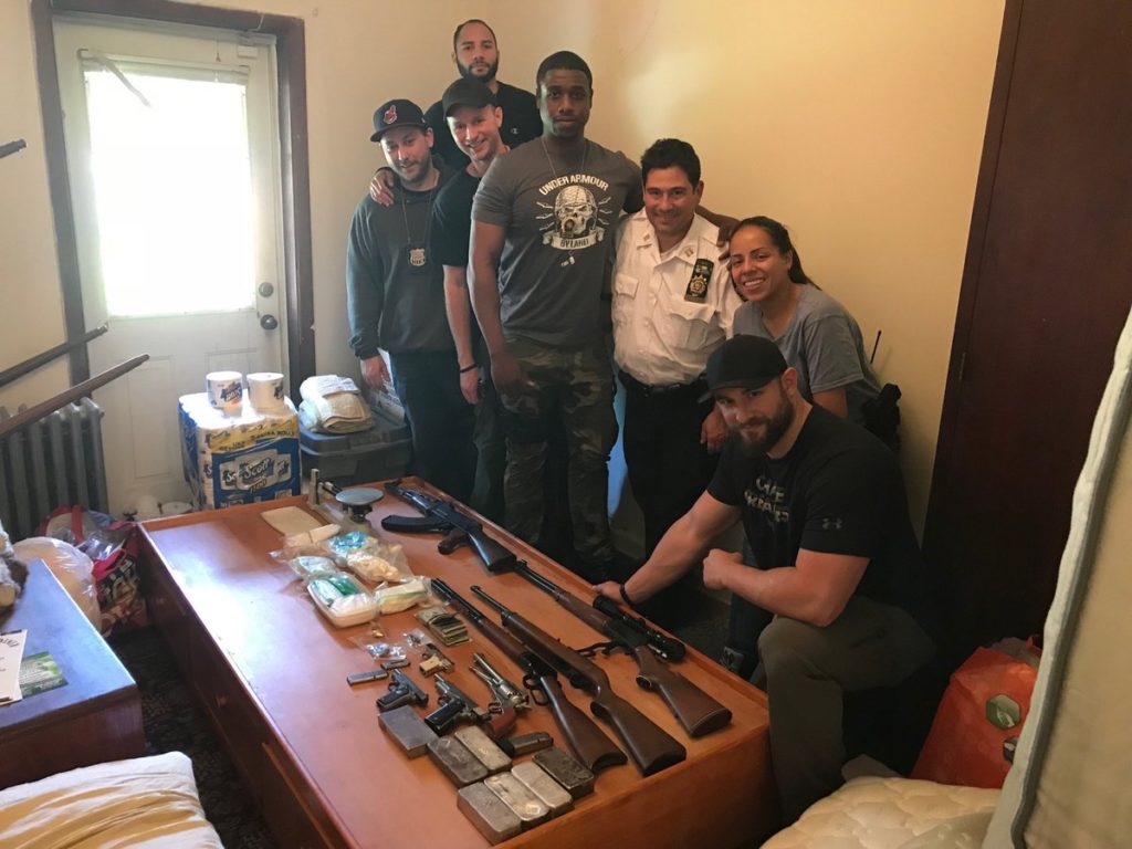 Members of NYPD Narcotics Borough Queens stand before some of the guns and drugs seized in a June 9 raid.