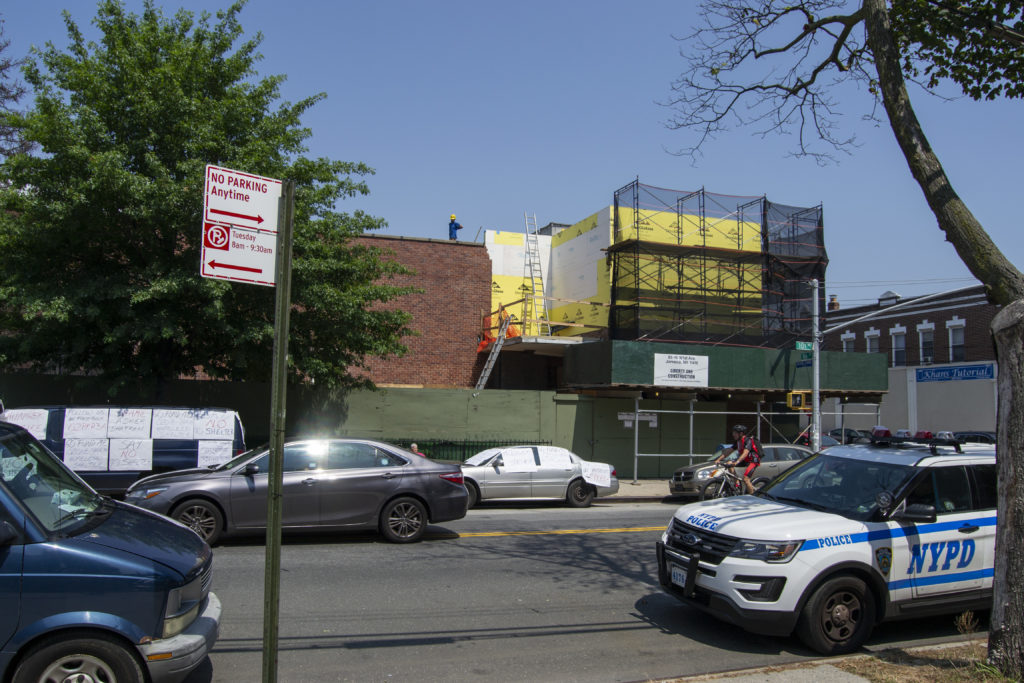 A construction worker looks down at the small crowd gathered for the press conference (Photo: Ryan Kelley/QNS).