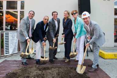 City officials dig into a pile of dirt during a groundbreaking ceremony at the Steinway library in Astoria.