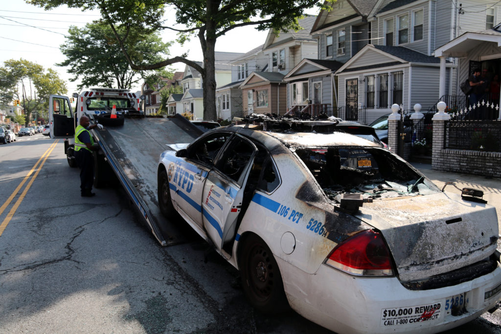 Officer checks out the burned out shell of her police car when it burst into flames while they were on patrol near the corner of 115 street and 107 ave. in the South Richmondhill section of Queens the officers were nt injured, the 2014 patrol car from the 106 pct, which is the pcts. plate reader car was damaged beyond repair alond the the officers gear and patrol cell phone. Photos by Robert Stridiron. 08/24/18