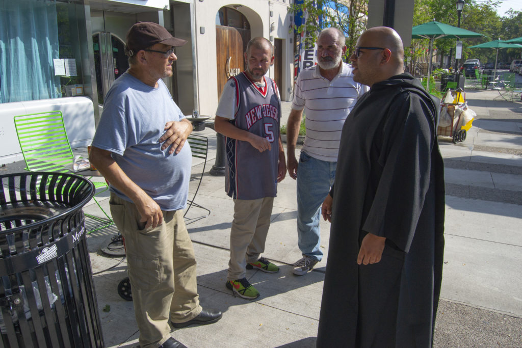 Lugo speaks with three homeless men at the 71st Avenue Plaza in ridgewood on Aug. 29. (Photo: Ryan Kelley/QNS)