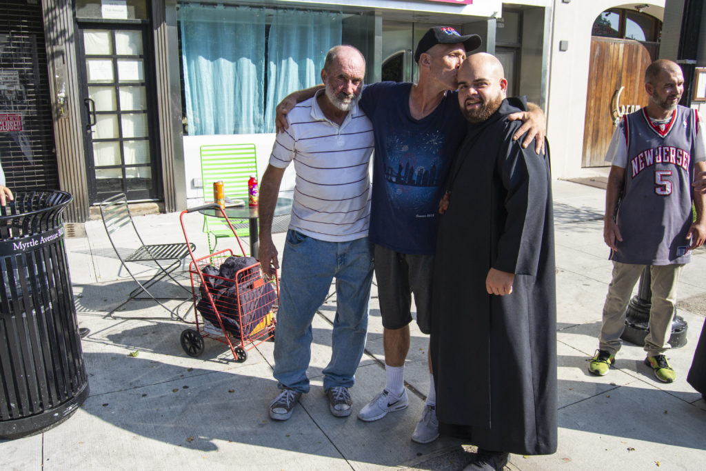 Jeremiah McCarthy (center) kisses father Lopez on the head at the 71st Avenue Plaza in Ridgewood on Aug. 29 (Photo: Ryan Kelley/QNS)