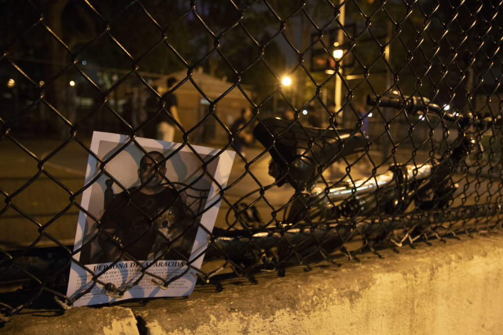 After handing out fliers to a group of men playing basketball in Jackson Heights, one of the players places a flier in the fence. 