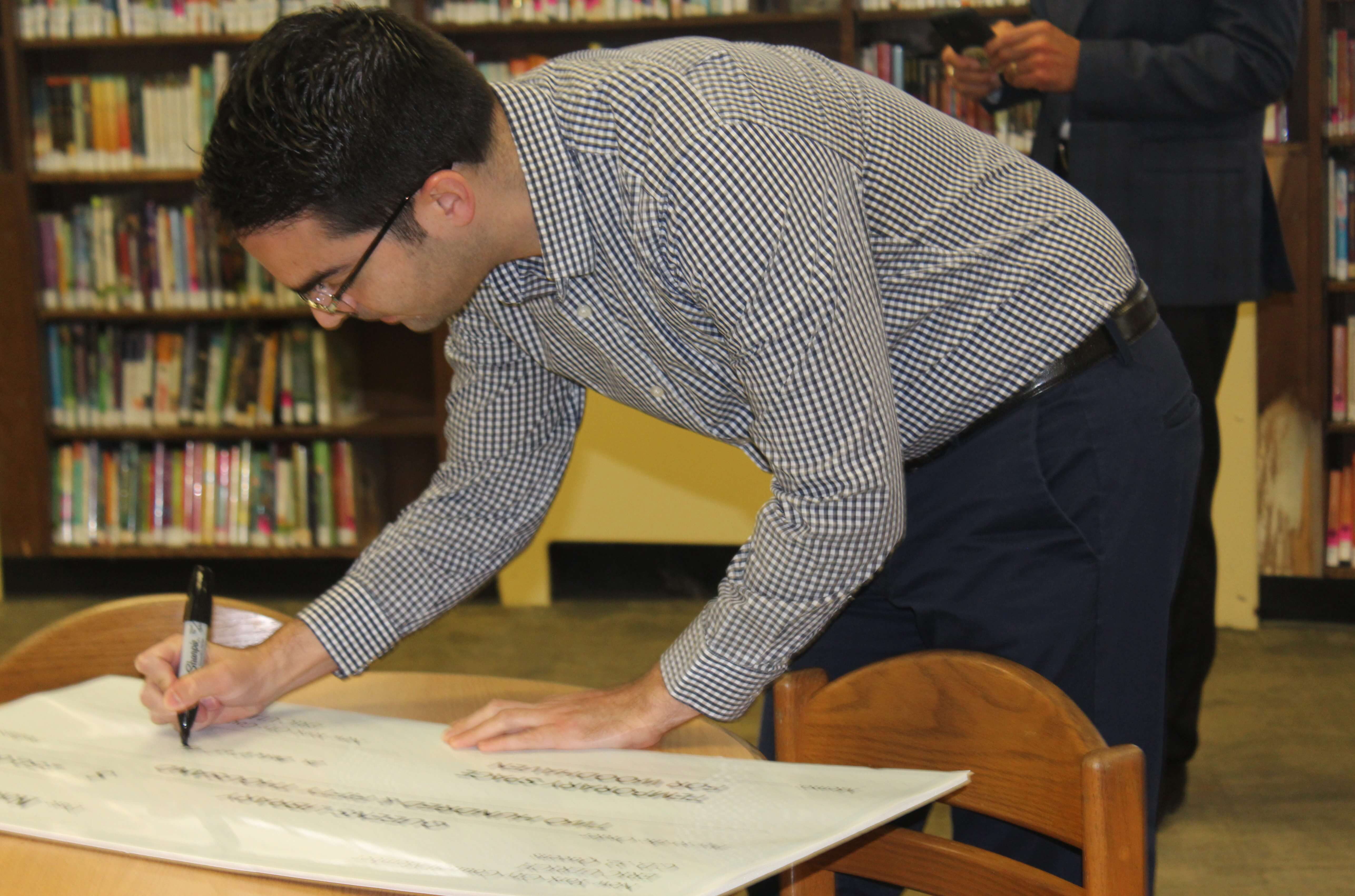 Councilman Eric Ulrich signs a check for $250,000 for Woodhaven Library.