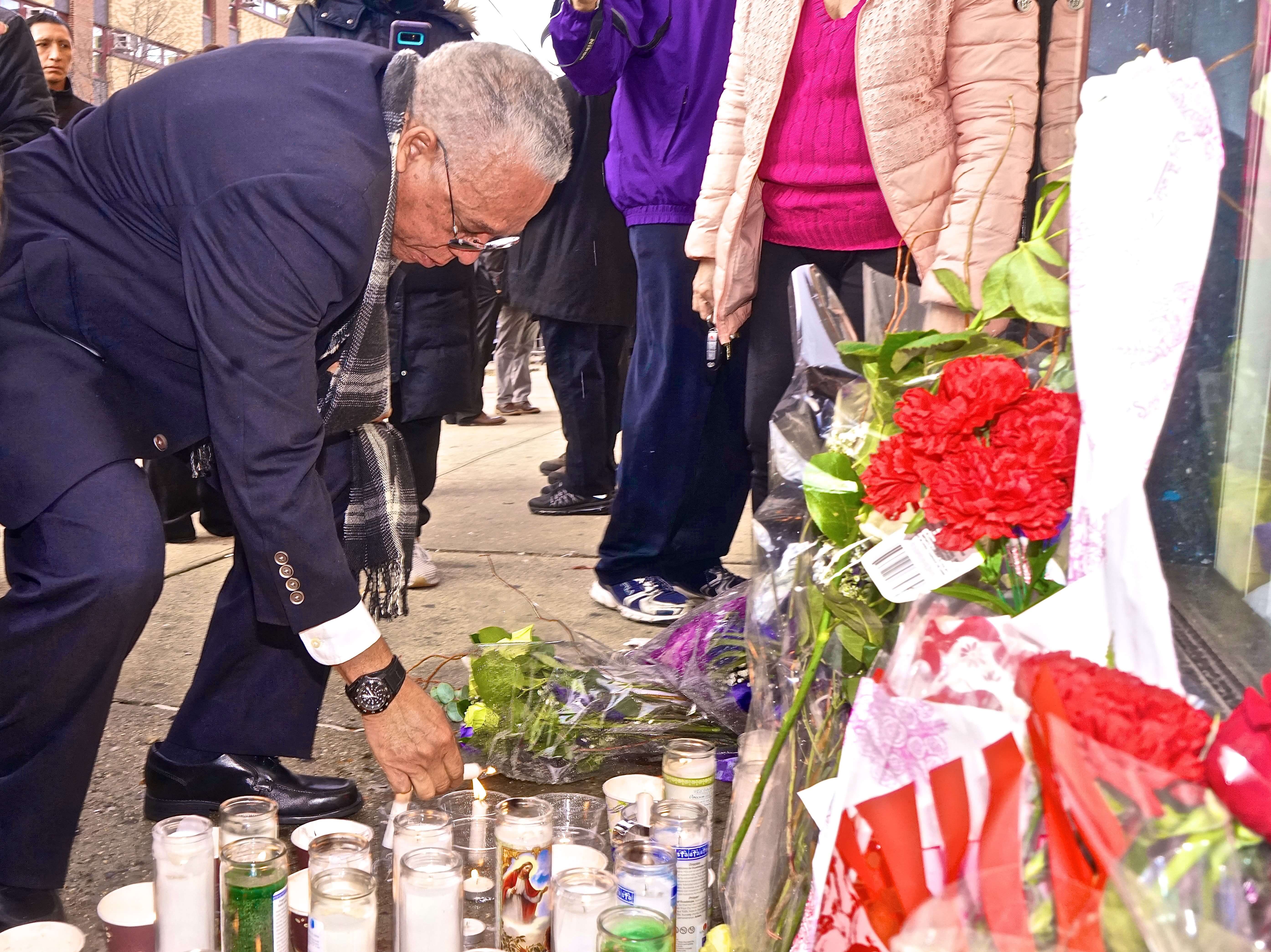 State Senator Jose Peralta's father lights a candle in front of the memorial in front of his late son's East Elmhurst district office on Nov. 25.