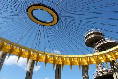 The repainted Tent of Tomorrow at the New York State Pavilion, with the iconic space needles towering in the background.