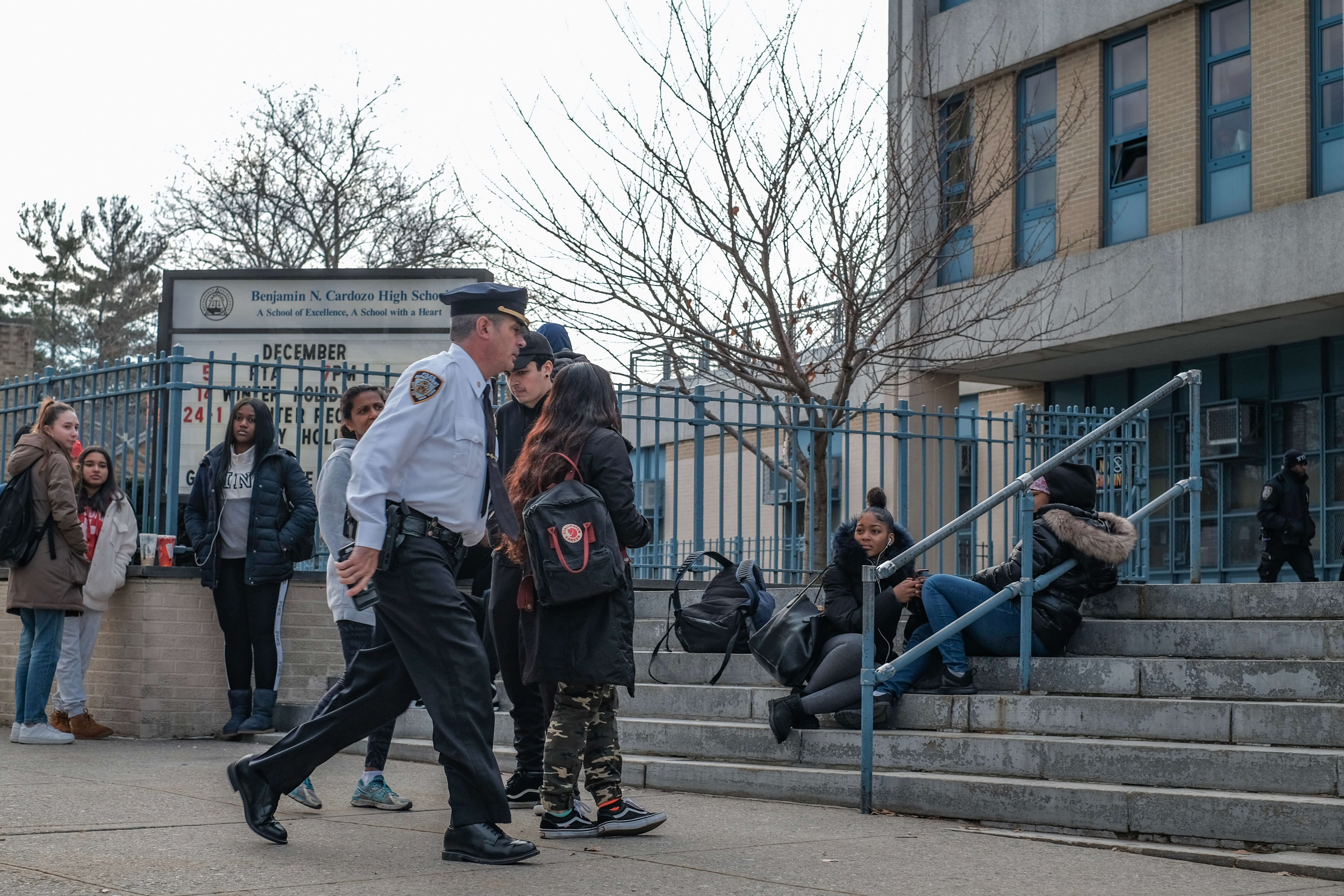 A police official walks past students outside of Benjamin Cardozo High School in Bayside during the Dec. 11 lockdown.