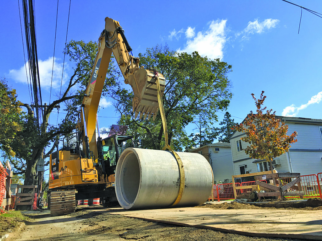 A backhoe hauls sewer equipment in southeast Queens.