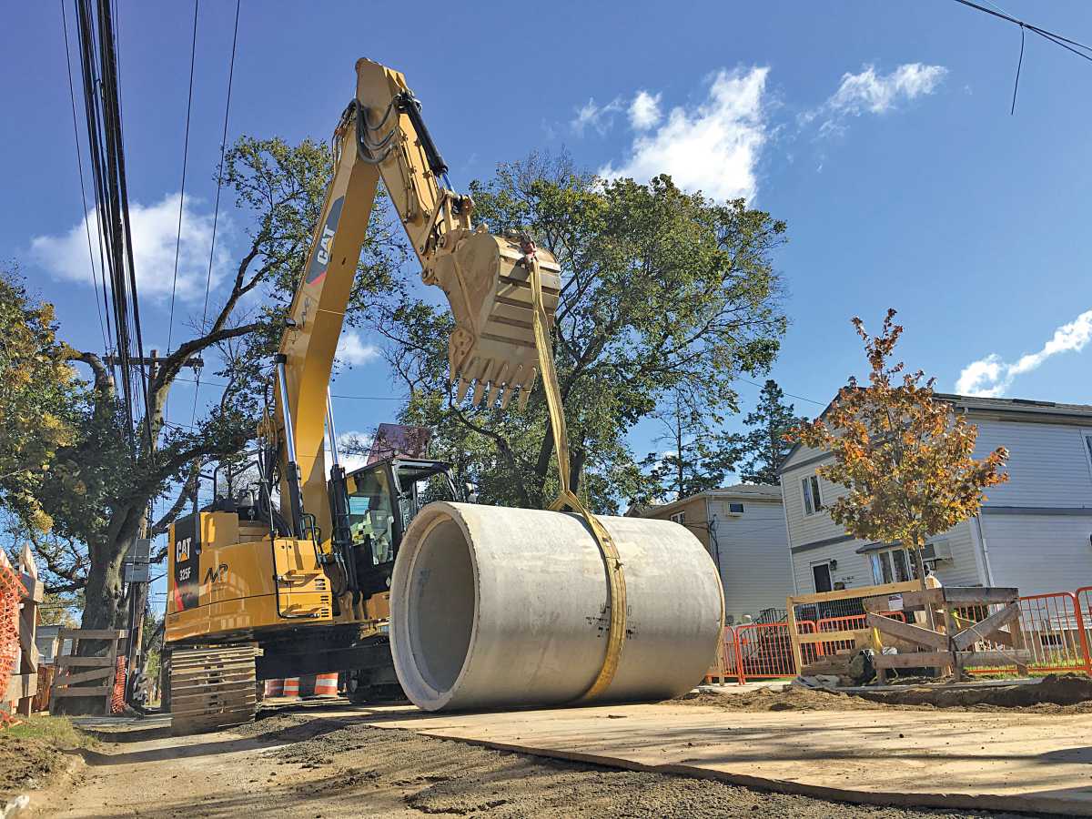 A backhoe hauls sewer equipment in southeast Queens.