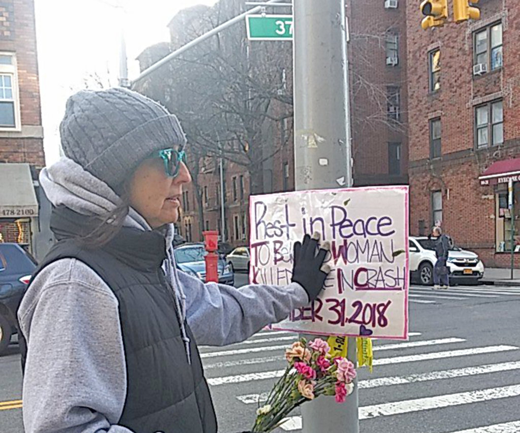 An activist places a memorial sign at the corner of 37th Avenue and 81st Street, where an allegedly unlicensed driver fatally ran over a woman on Dec. 31, 2018.