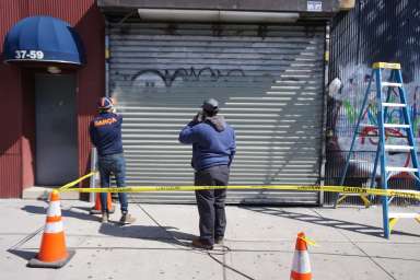 Councilman Francisco Moya at left) repaints a roll-down gate during a massive graffiti removal blitz in his district on March 20.