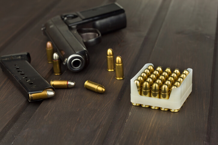 Handgun with ammunition on a dark wooden table