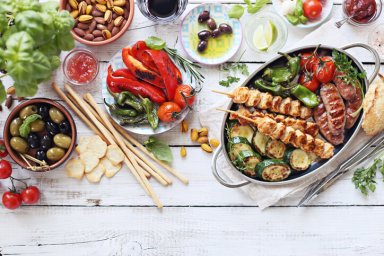Grilled meat, chicken skewers and sausage  with roasted vegetables and appetizers variety serving on party outdoor table. Mediterranean dinner table concept.