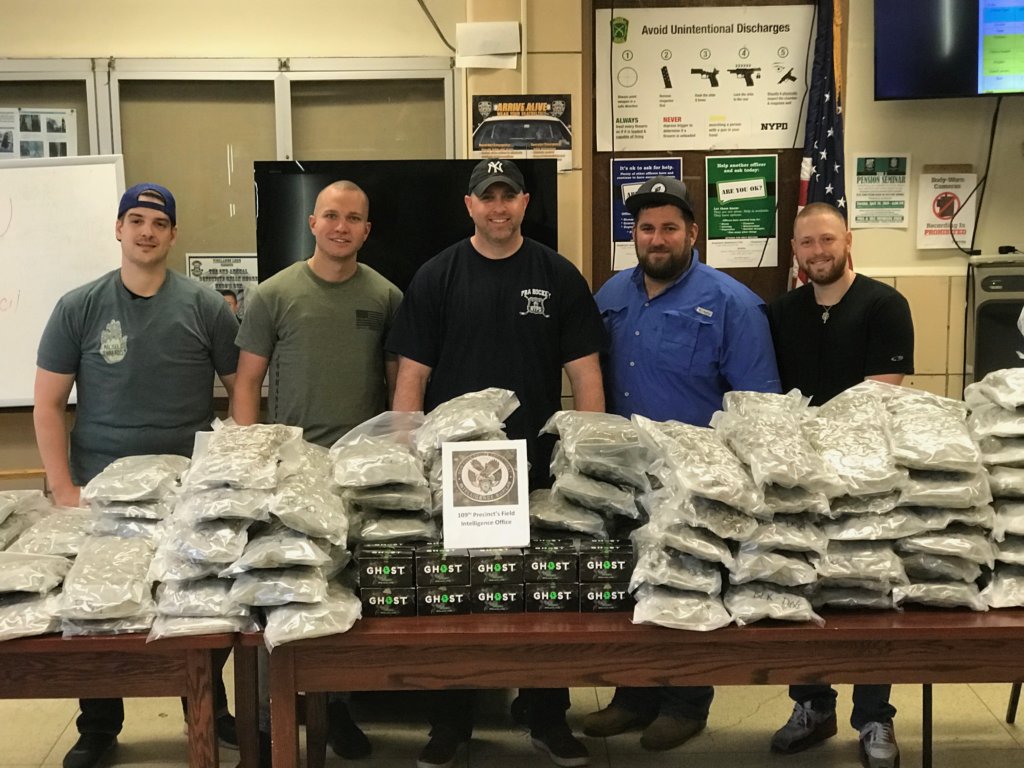 Police officers with stacks of vacuum-sealed bags containing $650,000 worth of pot seized in Flushing on May 8.
