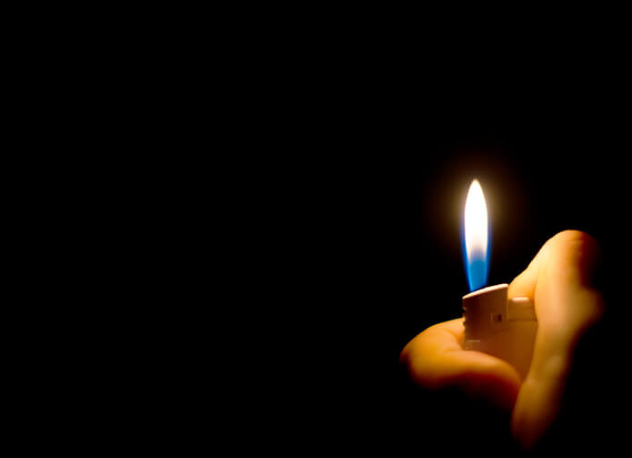Man’s hand holding a lighter. Place for text.