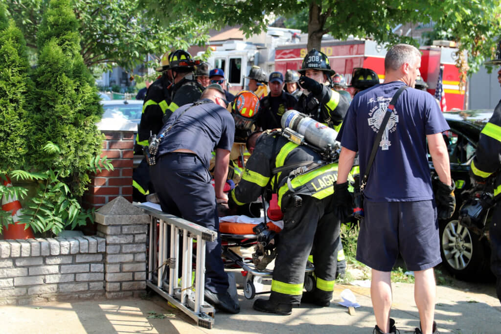 Firefighters and EMTs work to save a victim who jumped out of a burning home in Richmond Hill on July 21.