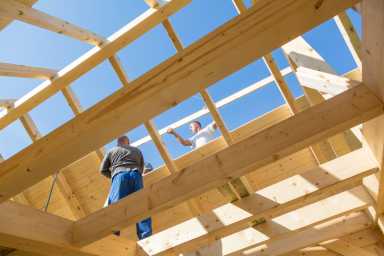 Builders at work with wooden roof construction.