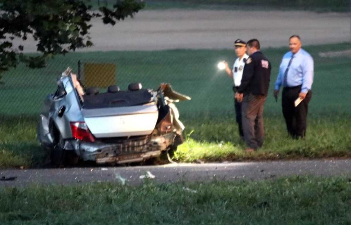 Police inspect the wreckage of the vehicle involved in a deadly one-car crash on South Conduit Avenue in Ozone Park on Aug. 4.