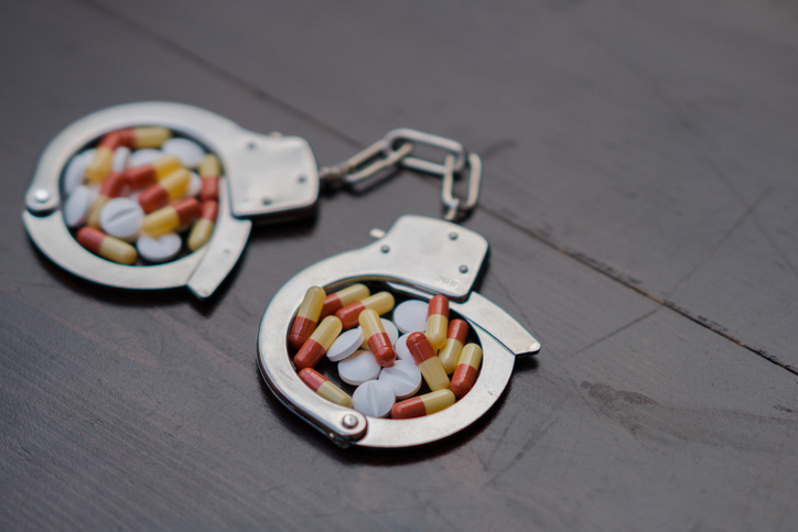 Handcuffs and pills. Selective focus