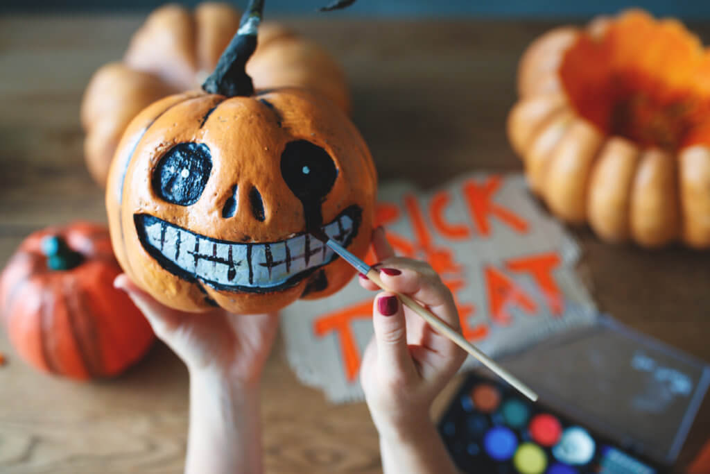 woman artist prepares for halloween and paints pumpkins