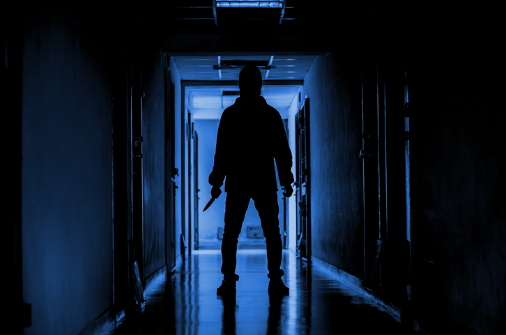 murder, kill and people concept – Criminal or murderer wearing a mask in silhouette holding knife inside a condo at crime scene