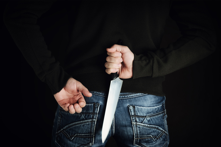 riminal with large sharp knife behind his back